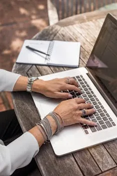 pexels-photo-1251834-1251834 Hands typing on a laptop at an outdoor wooden desk, symbolizing remote work.